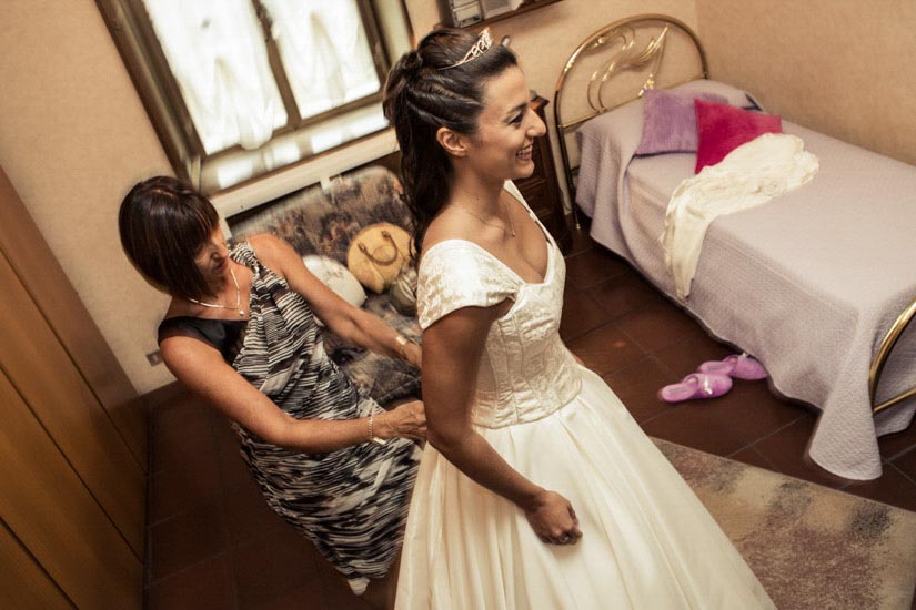 Fotografo matrimonio Torino: una mamma aiuta sua figlia a vestirsi per il suo matrimonio