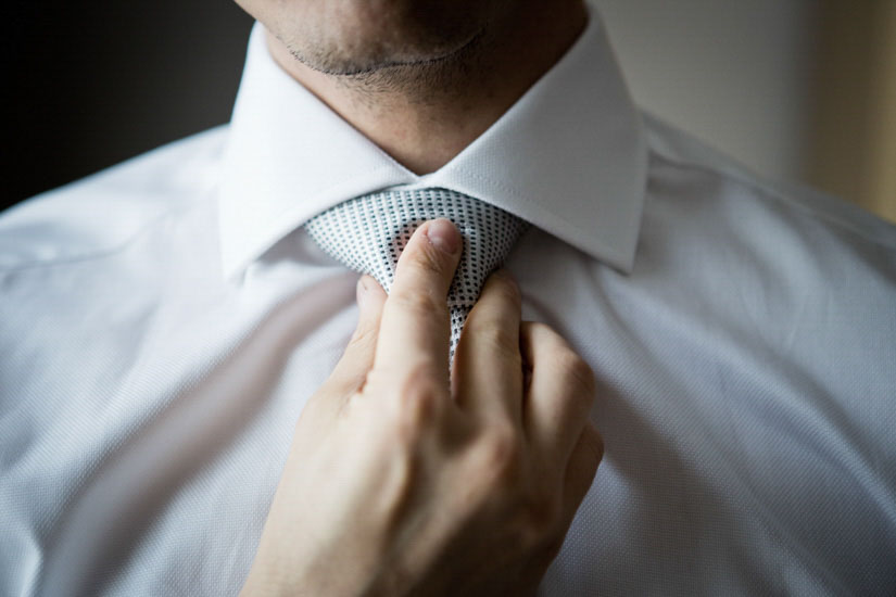 Fotografo matrimonio Torino: una mano stringe la cravatta per terminare i preparativi per il matrimonio