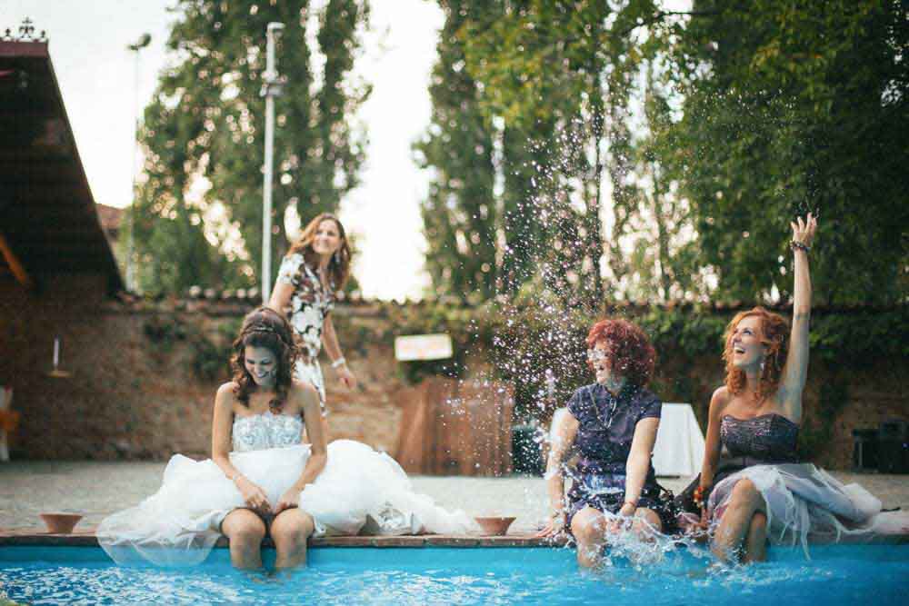Fotografo matrimonio Torino: due invitate scherzano con la sposa in piscina